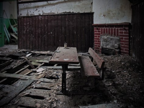 The brickwork fireplace in the smaller classroom at Leitir with an old school desk in the foreground