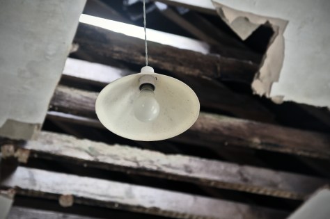 A light-bulb survives in the light fitting though the roof is collapsing